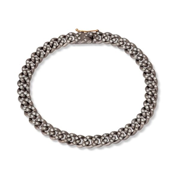 Muška narukvica iz groumette linije od Titanijuma, Dijamanata i 18 kt roze zlata. Moćna narukvica u potpunosti ručno izrađena od Titanijuma, gde serija od 29 zglobnih karika čini celu strukturu ove muževnog asesoara. Svaka karia sadrži četiri Dijamanta težine 0,01ct, a ukupna težine Dijamanata iznosi 1,05 ct. Narukvica se završava praktičnom kopčom od Titanijuma ukrašenom Dijamantima i dva sigurnosna osigurača u 18 kt roze zlatu. Dragoceni i važan dragulj potpisan od strane MANO|J., gde su Dijamanti i lakoća titanijuma pravi protagonisti.