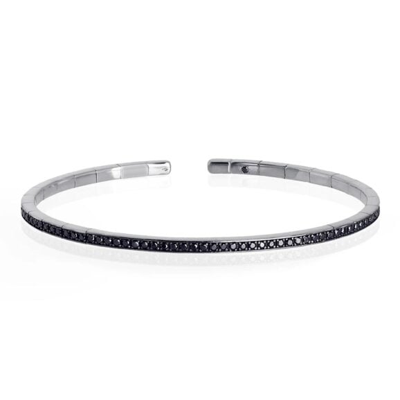 elastična, polu kruta narukvica od 18 kt belog zlata ukrašena sa ukupno 99 Crnih Dijamanata. Elastična narukvica je karakterisana dugim nizom od 99 crnih dijamanata ukupne težine od 0,99 karata koji prekrivaju deo cele narukvice. Unutar narukvice, kao garancija brenda MANO|J., postavljen je crni dijamant od 0,01 ct. Ova prefinjena, elegantna i savršeno nosiva narukvica odiše luksuzom. Ova narukvica se pravi u nekoliko veličina i odgovara i muškarcima i ženama. Istraži manje ženske narukvice ili šire muške narukvice sa Crnim Dijamantima, utkanim u 18 kt belo zlato.