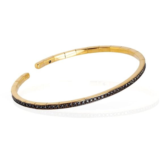 Zlatara as mano j. Zlatna narukvica m253 sprbrogbrt18kt p 2 mano j. Zlatna narukvica m253 Elastična, polu kruta narukvica od 18 kt žutog zlata ukrašena sa ukupno 99 crnih dijamanata. Elastična narukvica je karakterisana dugim nizom od 99 crnih dijamanata ukupne težine od 0,99 karata koji prekrivaju deo cele narukvice. Unutar narukvice, kao garancija brenda mano|j. , postavljen je crni dijamant od 0,01 ct. Ova prefinjena, elegantna i savršeno nosiva narukvica odiše luksuzom. Ova narukvica se pravi u nekoliko veličina i odgovara i muškarcima i ženama. Istraži manje ženske narukvice ili šire muške narukvice sa crnim dijamantima, utkanim u žuto zlato.