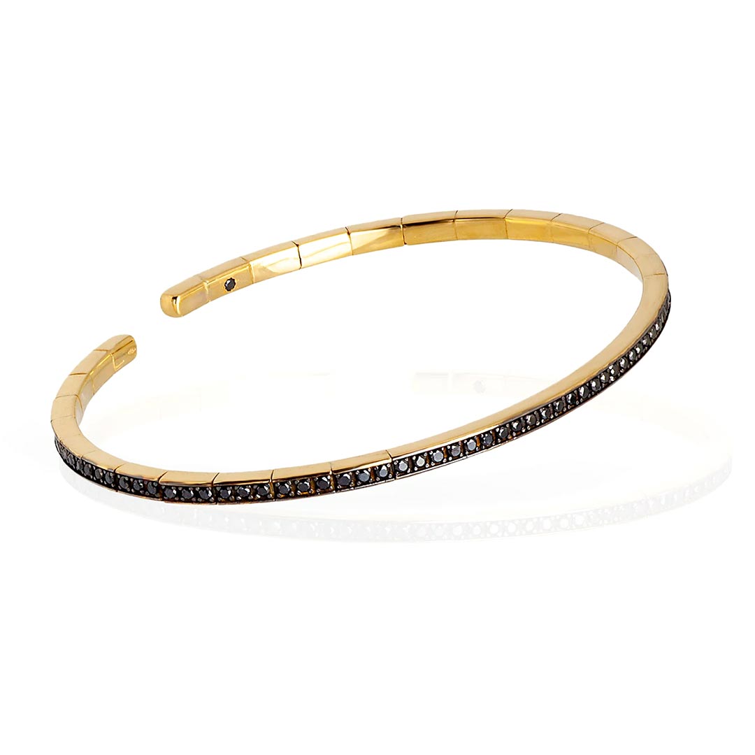 Kruta spring narukvica od zlata, sa dijamantima, model sprbrogbrt18kt_p Elastična, polu kruta narukvica od 18 kt žutog zlata ukrašena sa ukupno 99 crnih dijamanata. Elastična narukvica je karakterisana dugim nizom od 99 crnih dijamanata ukupne težine od 0,99 karata koji prekrivaju deo cele narukvice. Unutar narukvice, kao garancija brenda mano|j. , postavljen je crni dijamant od 0,01 ct. Ova prefinjena, elegantna i savršeno nosiva narukvica odiše luksuzom. Ova narukvica se pravi u nekoliko veličina i odgovara i muškarcima i ženama. Istraži manje ženske narukvice ili šire muške narukvice sa crnim dijamantima, utkanim u žuto zlato.