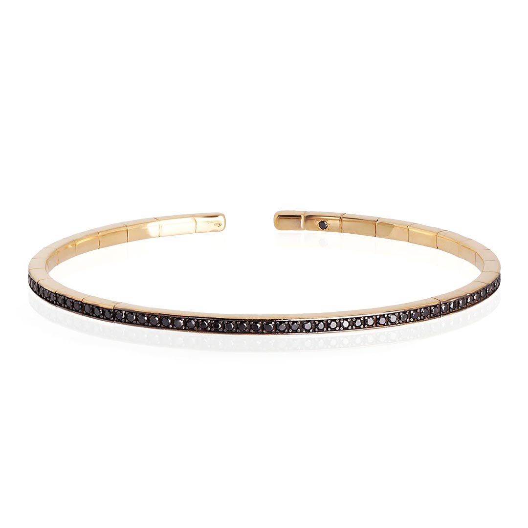 Kruta spring narukvica od zlata, sa dijamantima, model sprbrogbrt18kt_p Elastična, polu kruta narukvica od 18 kt žutog zlata ukrašena sa ukupno 99 crnih dijamanata. Elastična narukvica je karakterisana dugim nizom od 99 crnih dijamanata ukupne težine od 0,99 karata koji prekrivaju deo cele narukvice. Unutar narukvice, kao garancija brenda mano|j. , postavljen je crni dijamant od 0,01 ct. Ova prefinjena, elegantna i savršeno nosiva narukvica odiše luksuzom. Ova narukvica se pravi u nekoliko veličina i odgovara i muškarcima i ženama. Istraži manje ženske narukvice ili šire muške narukvice sa crnim dijamantima, utkanim u žuto zlato.