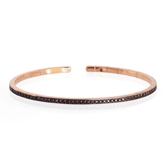 elastična, polu kruta zlatna narukvica od 18 kt roze zlata ukrašena sa ukupno 99 Crnih Dijamanata. Elastična narukvica je karakterisana dugim nizom od 99 crnih dijamanata ukupne težine od 0,99 karata koji prekrivaju deo cele narukvice. Unutar narukvice, kao garancija brenda MANO|J., postavljen je crni dijamant od 0,01 ct. Ova prefinjena, elegantna i savršeno nosiva narukvica odiše luksuzom. Ova narukvica se pravi u nekoliko veličina i odgovara i muškarcima i ženama. Istraži manje ženske narukvice ili šire muške narukvice sa Crnim Dijamantima, utkanim u roze zlato.