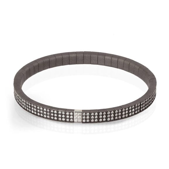 Loop narukvica za muškarce od titanijuma, 18 kt belog zlata i belih dijamanata. Duga serija zglobnih elemenata od titanijuma povezanih međusobno čini elastičnu narukvicu. Svaki element je ukrašen sa 6 belih dijamanata, ukupne težine od 3.12 ct. Da bi se dodatno obogatila narukvica, umetnut je element od 18 kt belog zlata sa 6 belih dijamanata, ukupne težine od 6 tačaka. Dragoceni dragulj u kome su zlatarski majstori, inovacije i poznavanje materijala brenda MANO|J., uspeli da stvore remek-delo visokih vrednosti.