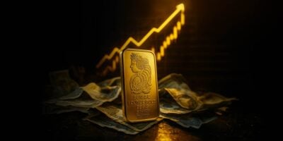 Zlatna poluga pamp iznad papirnog novca a iza čart koji ide nagore