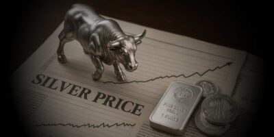 Statua srebrnog bika na novinama na kojima stoji natpis silver price, odnosno cena srebra, a na novinama se nalaze i srebrne kovanice bečka filharmonija i srebrna poluga