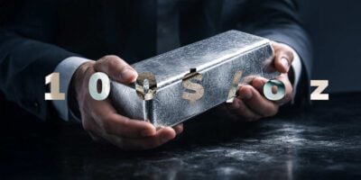 Muške ruke drže polugu od srebra sa natpisom 100$/oz